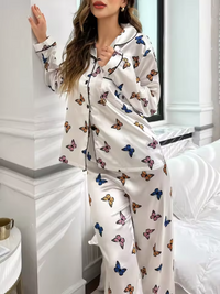 Butterfly print satin pyjama set with notch collar and contrast piping, worn by a woman by a window
